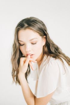 A serene portrait of a woman in white, showcasing contemplative beauty and grace in soft lighting.