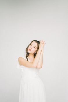 Elegant woman posing in a serene atmosphere with a white dress, expressing beauty and grace.