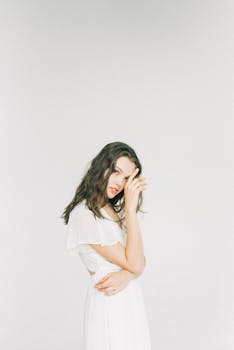 一位美丽的女子身穿白色连衣裙，在极简主义背景下优雅地摆出姿势