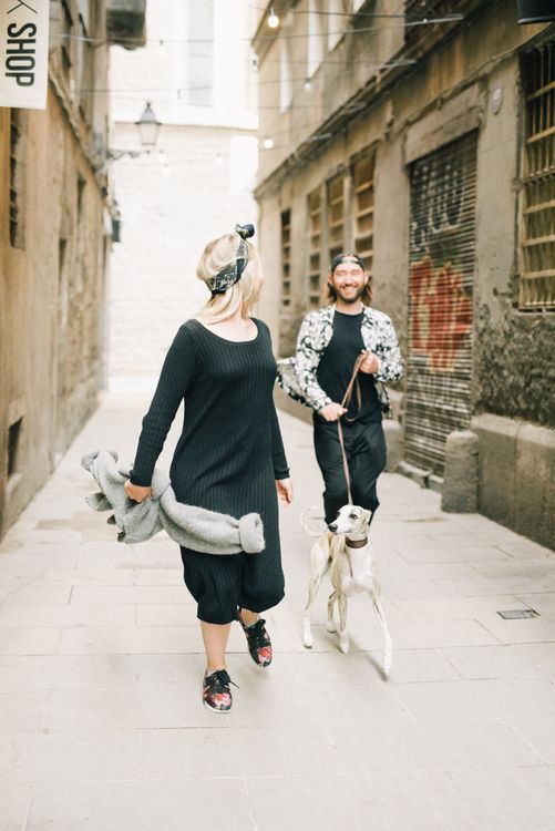 A joyful couple walking their dog together in an urban alleyway