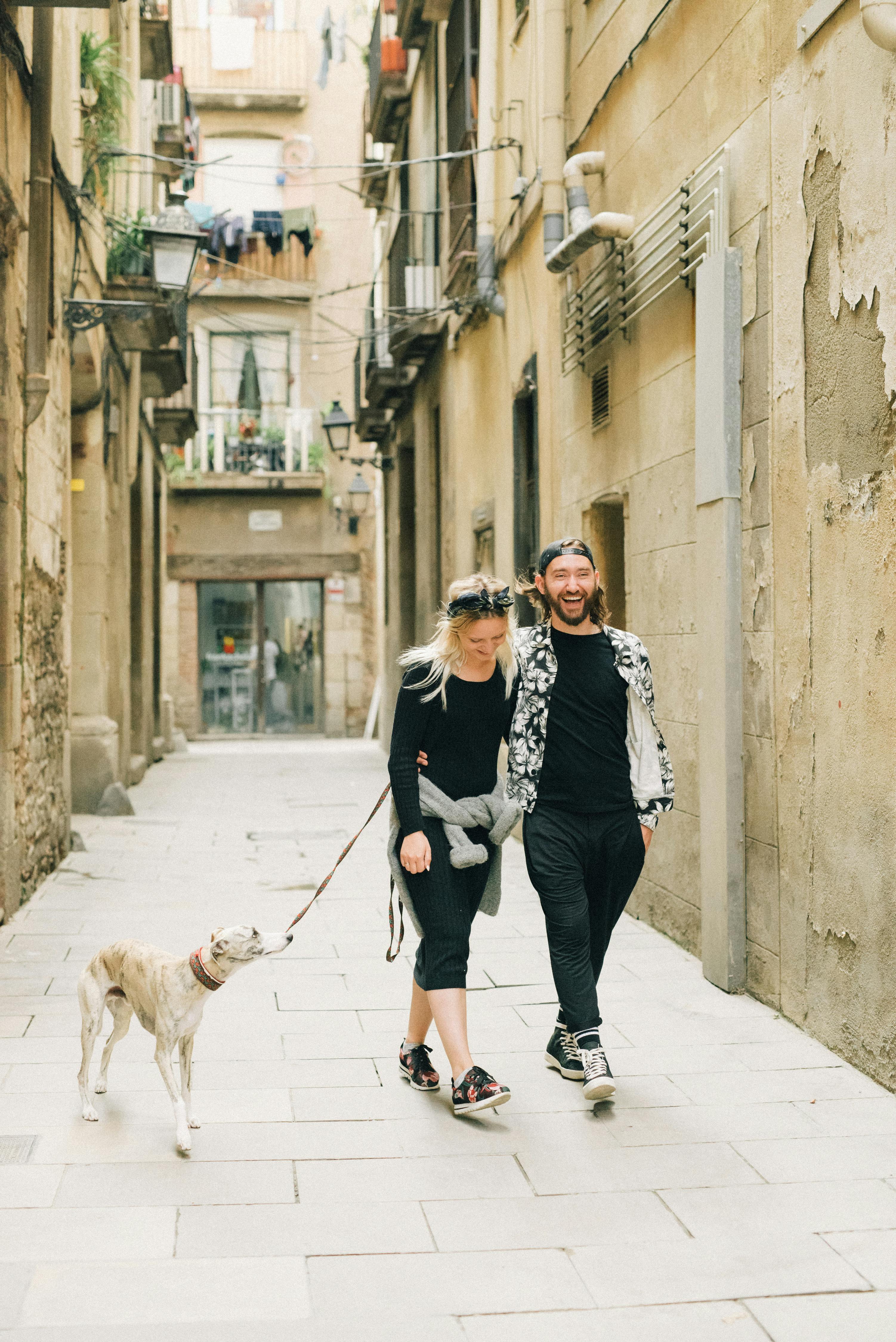 a couple walking on the street together with their pet dog