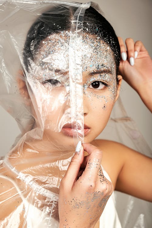 Young Asian woman face covered of raincoat and tinsel