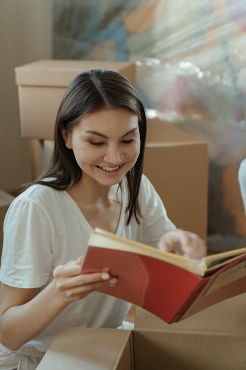 Woman in White Crew Neck T-shirt Holding Red Book