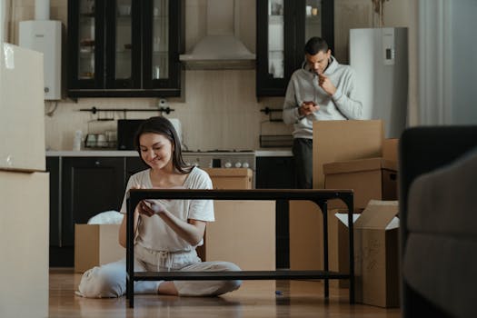 A young couple unpacking boxes in their new apartment kitchen, settling into a cozy home.