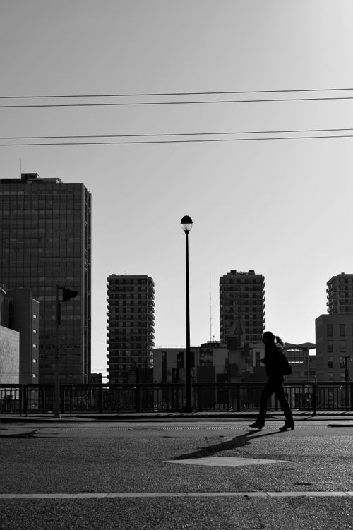 Free Black and white silhouette of anonymous female walking along asphalt roadway in city Stock Photo