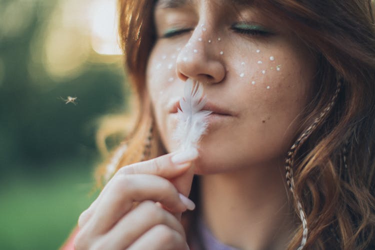 Calm Woman With Makeup Holding Feather On Lips