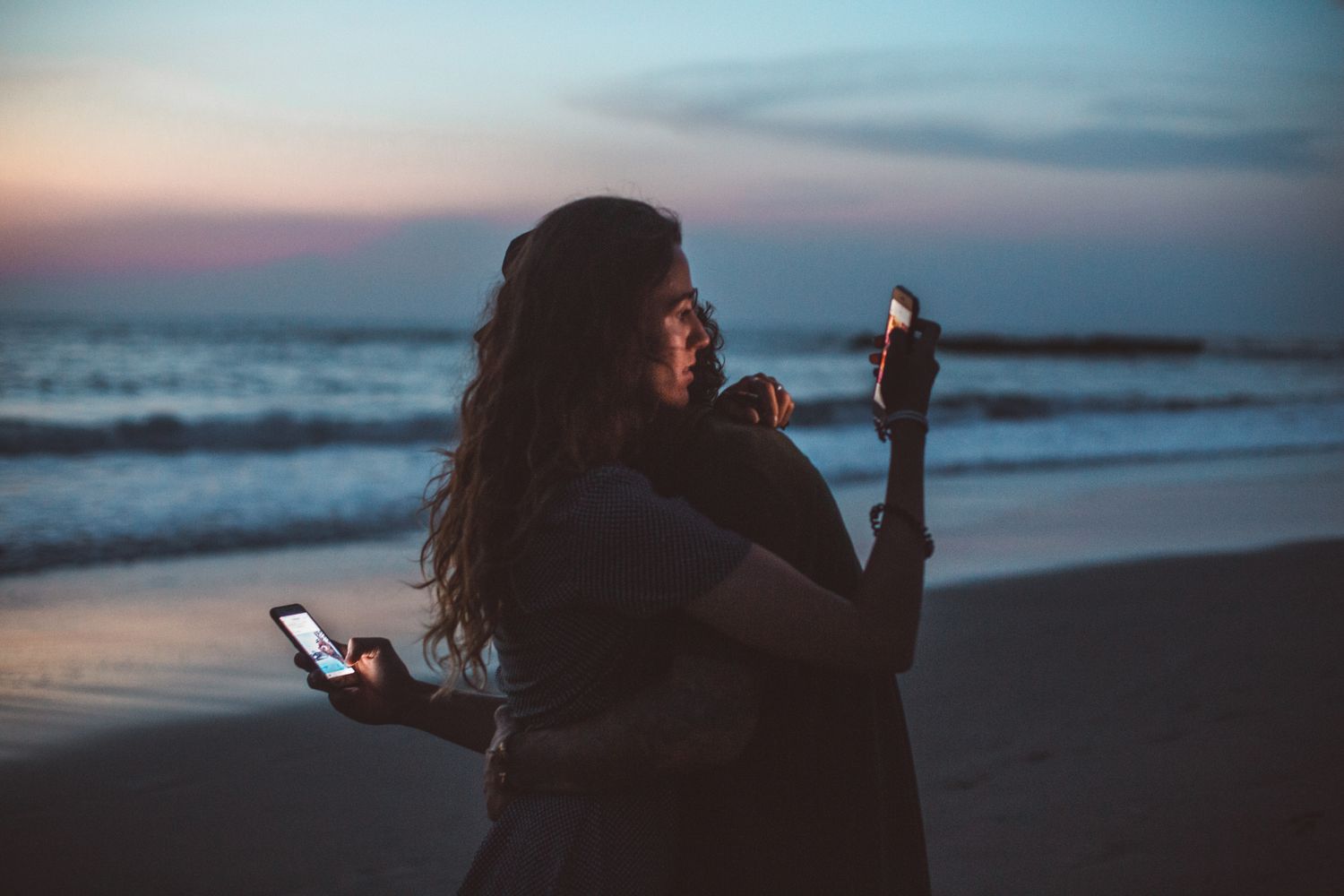Adults using a smartphone privately while travelling at sunset