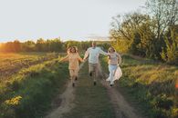Full body of excited young friends smiling while running together with holding hands towards camera