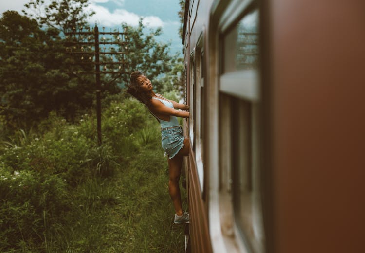 Ethnic Woman Leaning Out Of Train Standing In Exit Door