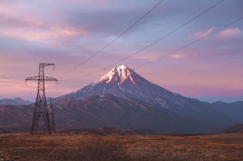 Free High voltage power lines against mountains in sunset Stock Photo