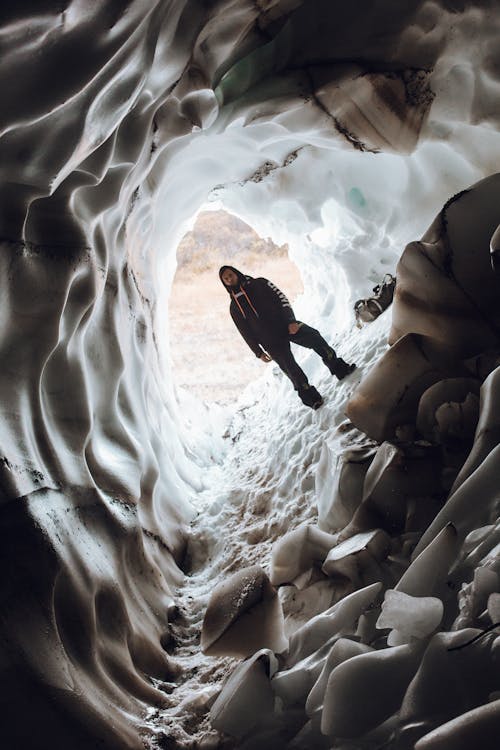 Unrecognizable man in winter outerwear standing in ice surface of cave