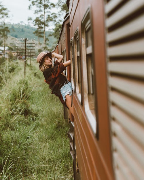 Young woman riding train leaning out of wagon