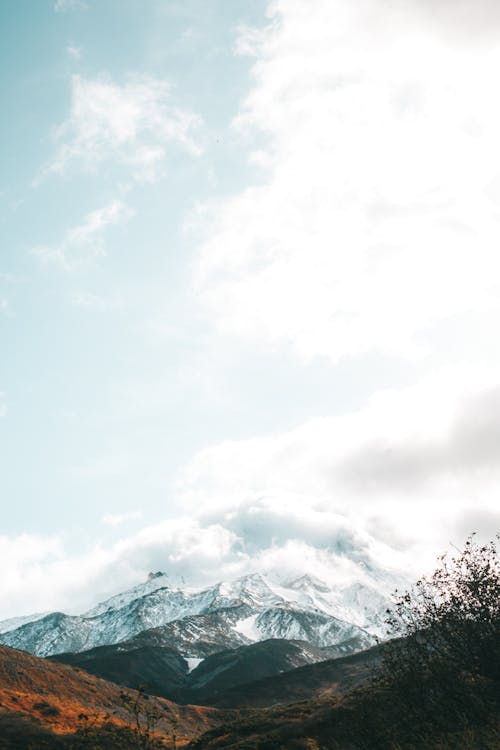 Wonderful view of highland with majestic mountains peaks covered with snow and clouds on sunny winter day