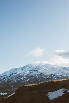 Breathtaking view of majestic mountains covered with snow and located on rocky highland against clear blue sky