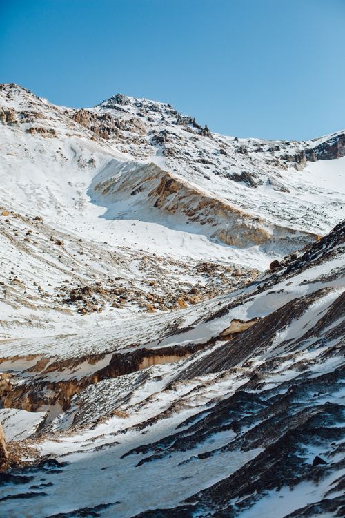 Free From below magnificent scenery of rough mountain slope covered with snow against cloudless blue sky Stock Photo