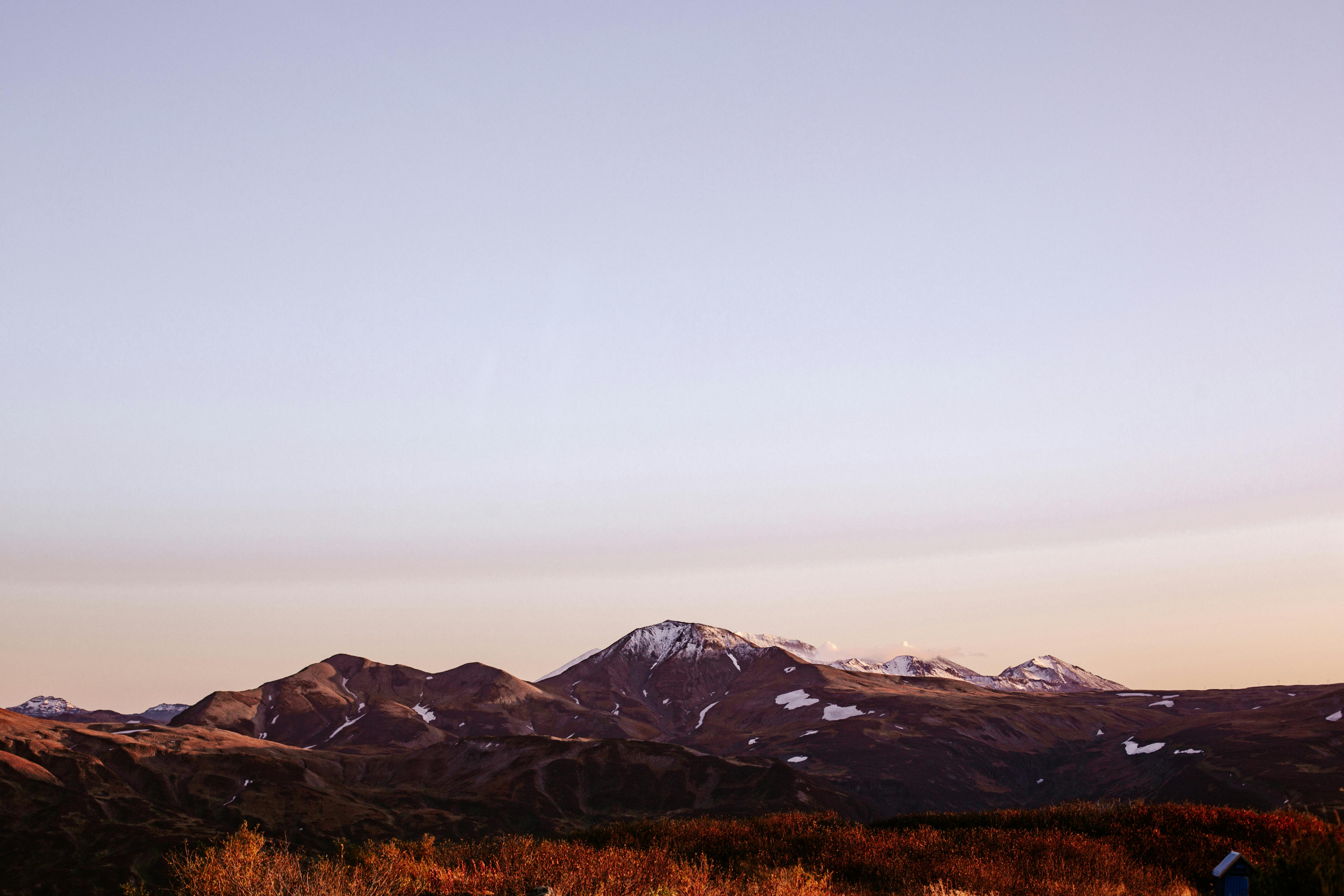 Peaceful view of a snow-capped mountain range at twilight with a clear sky.