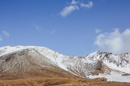 Magnificent view of snowy mountain range on bright day against blue sky with few clouds