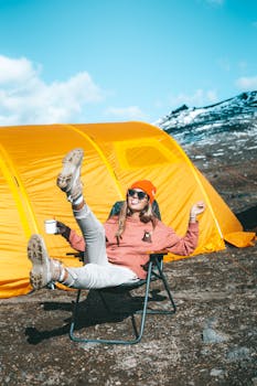 一位穿着温暖的女人在充满活力的黄色帐篷旁享受户外阳光
