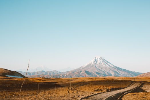 万里无云的天空下，高耸的雪山、皑皑的峰顶与沙漠乡村道路交织成一幅如画的风景