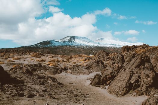 远处的山脉风景如画，山坡上覆盖着积雪，云层下是岩石地形环绕