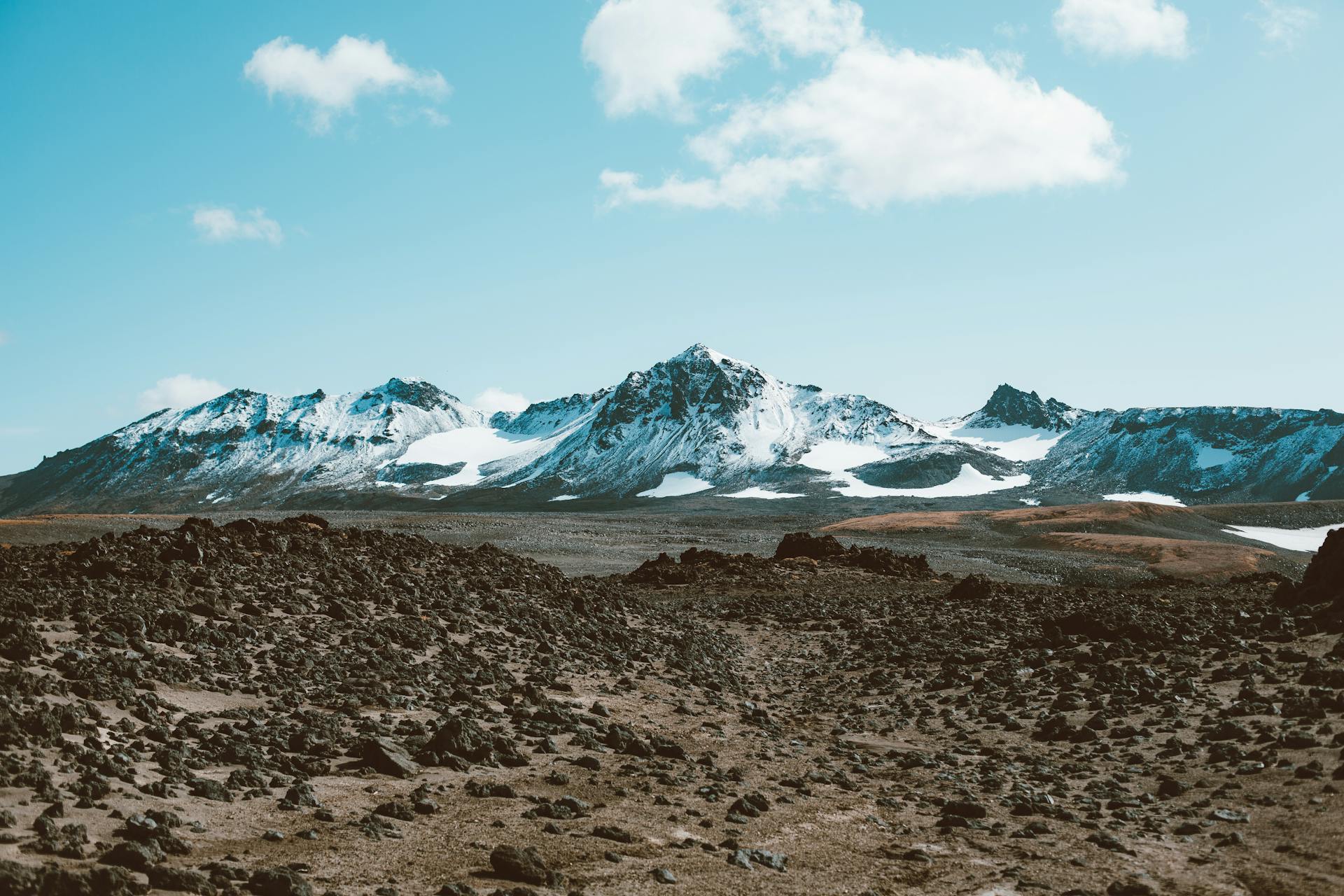 Amazing view of distant mountain ridge covered with snow and desert rocky valley under blue sky