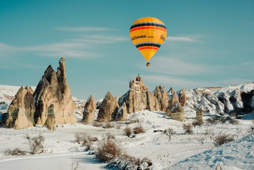 Yellow and Red Hot Air Balloon Flying Over Rock Formations