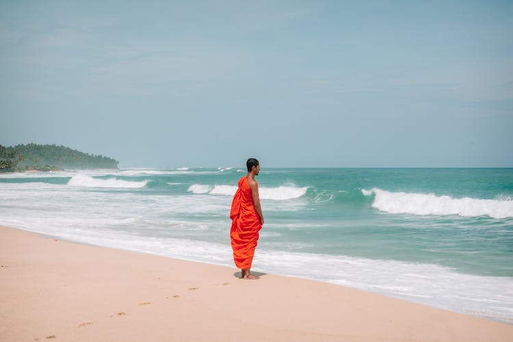 Asian Man In Traditional Orange Dress On Beach