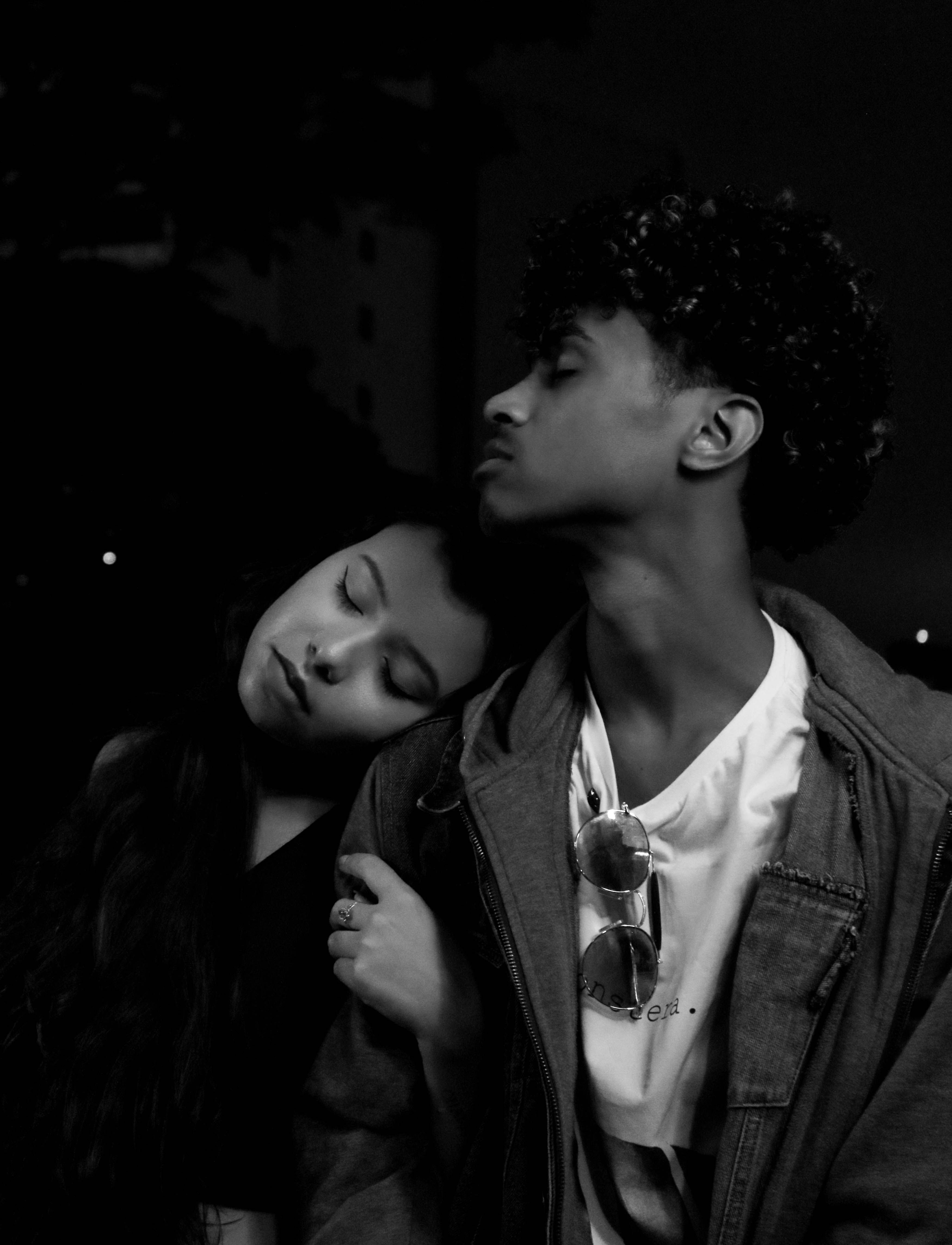Black and white of young ethnic man and woman with closed eyes standing close to each other