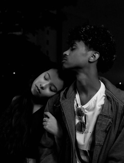 Black and white of young ethnic man and woman with closed eyes standing close to each other