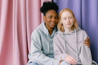 一对跨种族夫妇面带微笑坐在一起，背景是柔和的窗帘