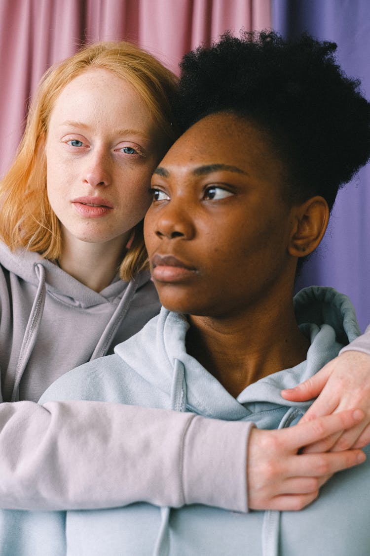 Women Wearing Hoodies Near The Curtains