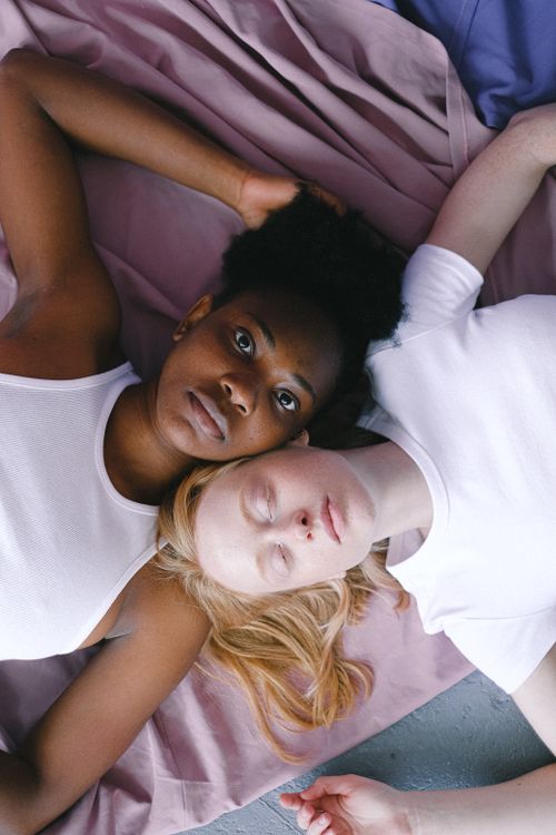 Free Close-up portrait of two women lying together, embracing diversity and connection. Stock Photo