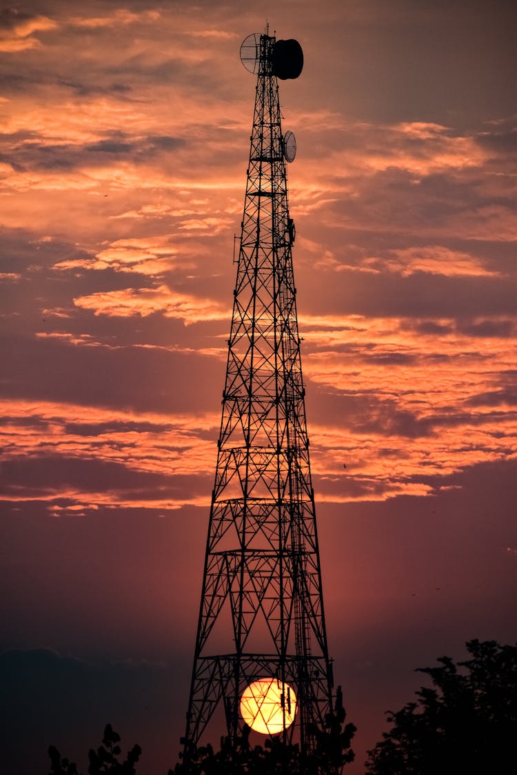 Sun Setting Over Field With Telecommunications Tower