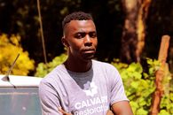 A thoughtful man outdoors with a blurred natural background.