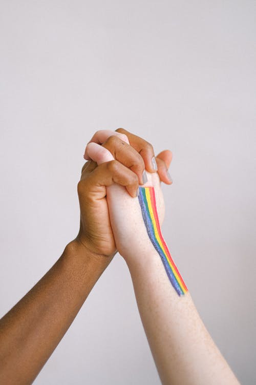 Free Persons Hand with Lgbt Pride Flag Holding Womans Hand Stock Photo