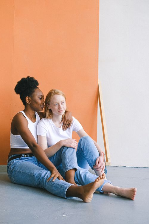 Free Loving interracial couple sitting and embracing on the floor indoors. Stock Photo