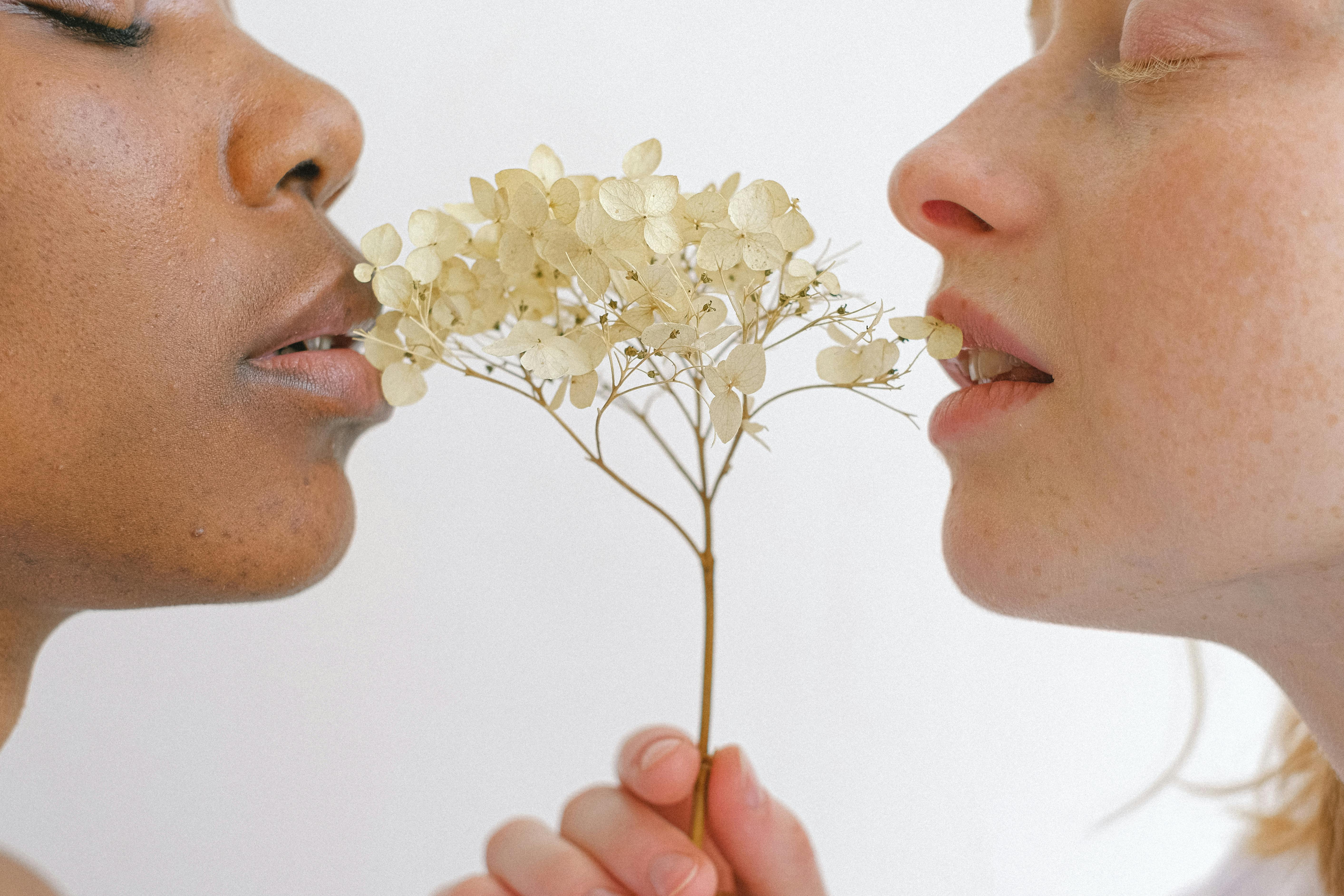 women with flowers touching their lips