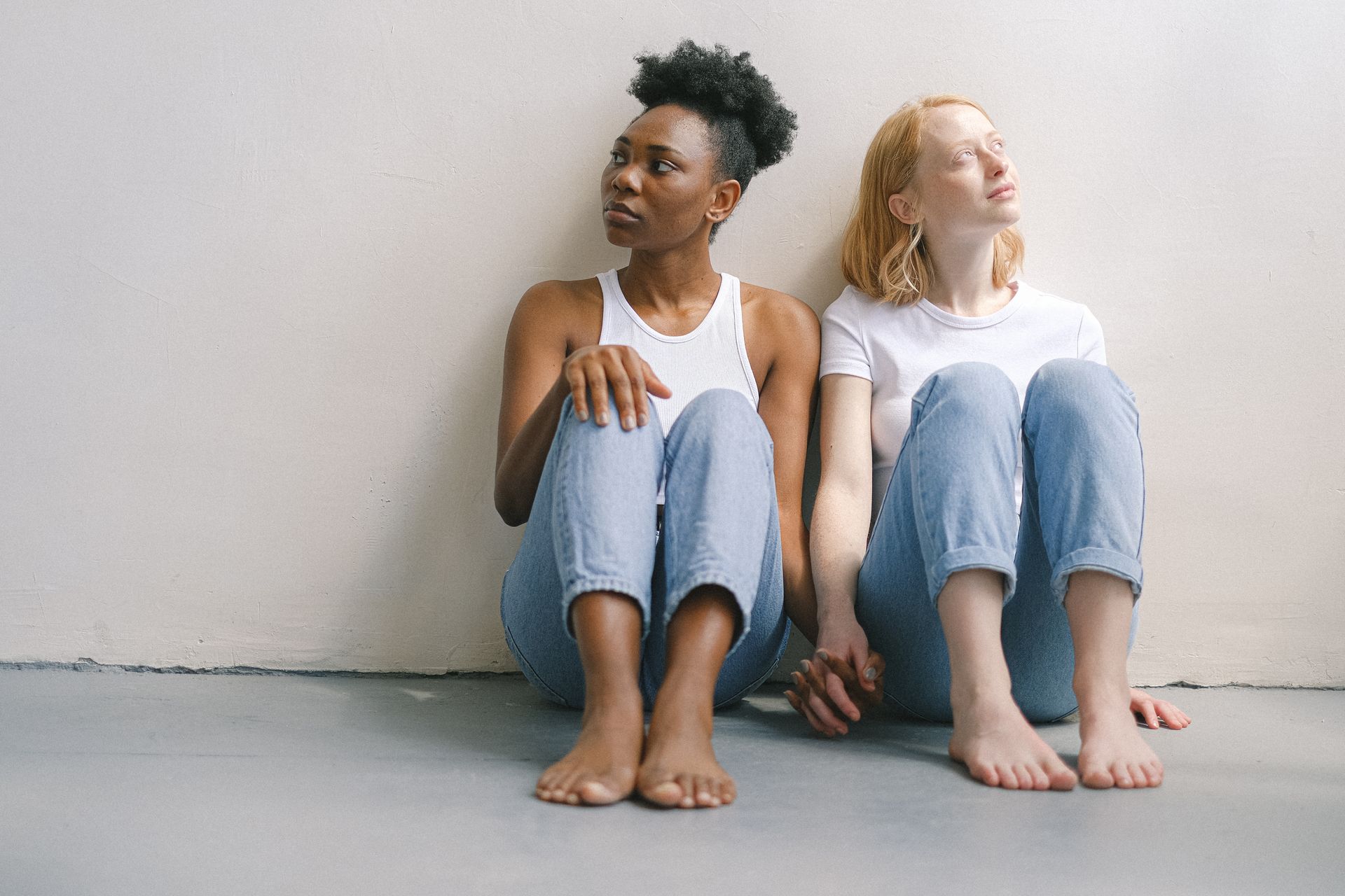 Interracial couple sitting barefoot on the floor, depicting love and togetherness.