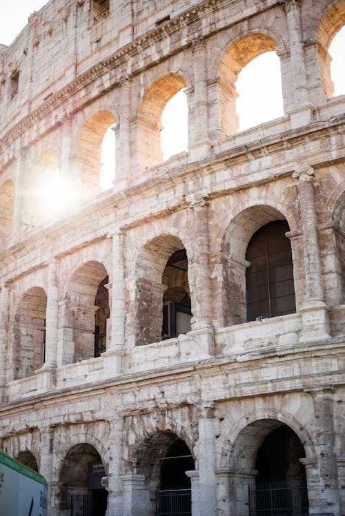 Amazing facade of famous Colosseum with sunbeam coming through one of weathered arches on bright day