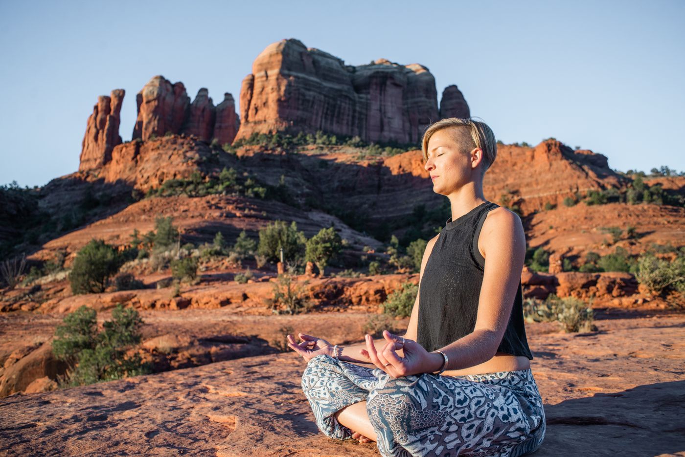 Woman meditating among Sedona’s sunlit red rocks