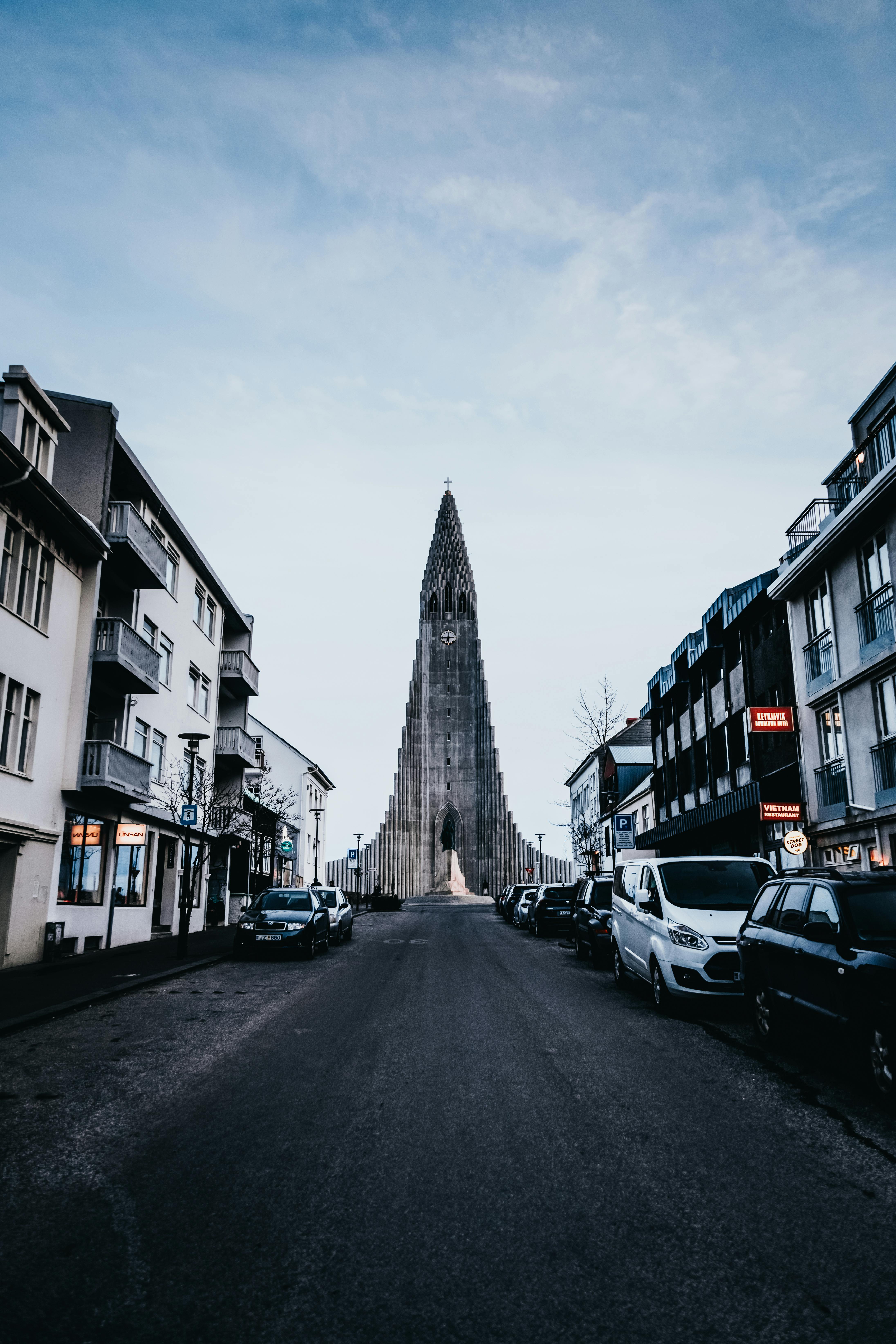 Majestic view of Hallgrimskirkja church in Reykjavik, Iceland, from the street with urban buildings surrounding.