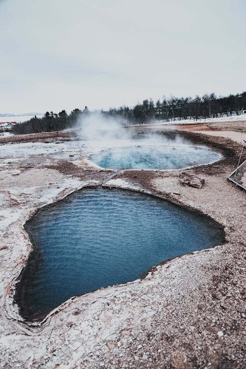 From above of Blesi pool and Fata erupting geyser located at Geysir Hot Springs in Iceland against cloudy sky