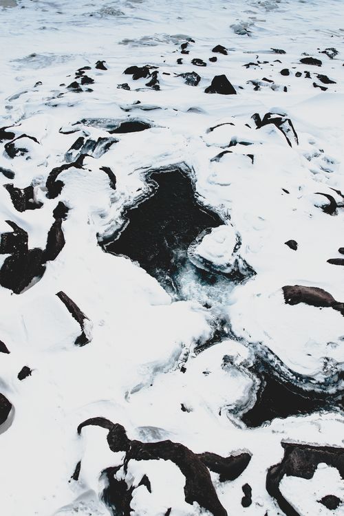 Free From above of frozen river surface covered with snow with ice and rocks on winter day Stock Photo