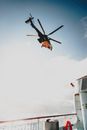 Low angle of helicopter with spinning rotor blades in light blue sky above cruise ship in high sea