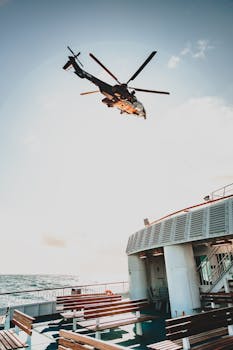 From below of bottom part of modern helicopter with spinning rotor blades above wooden benches on cruise ship in high ocean