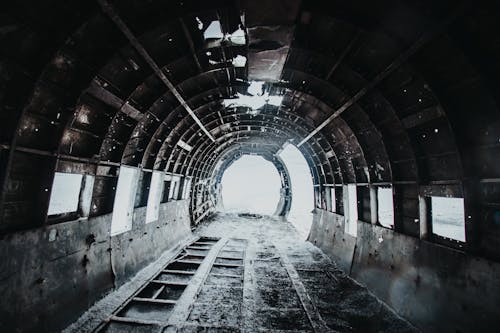 Interior of desolated old empty destructed airplane with dirty floor covered with snow and holes on walls and ceiling