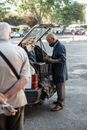 Male in face mask taking things out of car trunk
