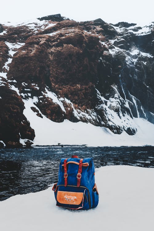 Small blue backpack on shore of river