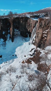 冬日晴空下，雪地、悬崖与无叶灌木构成壮丽景色