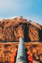 Picturesque view of mountain ridge covered with snow located near calm lake against metal pipe on sunny day with cloudless sky